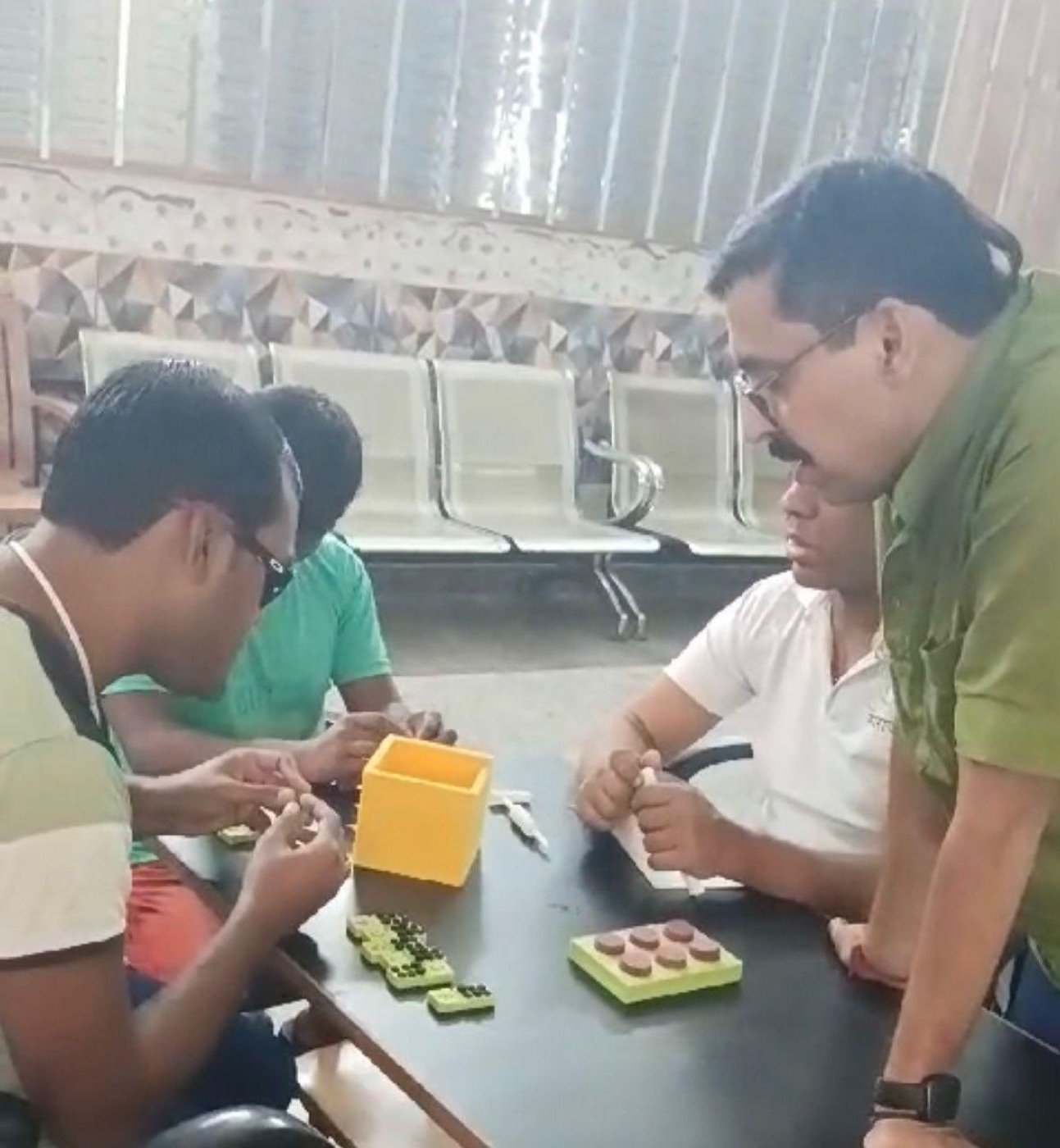Four learners at Divya Jyoti Niwas around a table, working through the Math Kit &mdash; Braille number tiles, the tactile abacus tray and the kit&rsquo;s storage box in front of them.